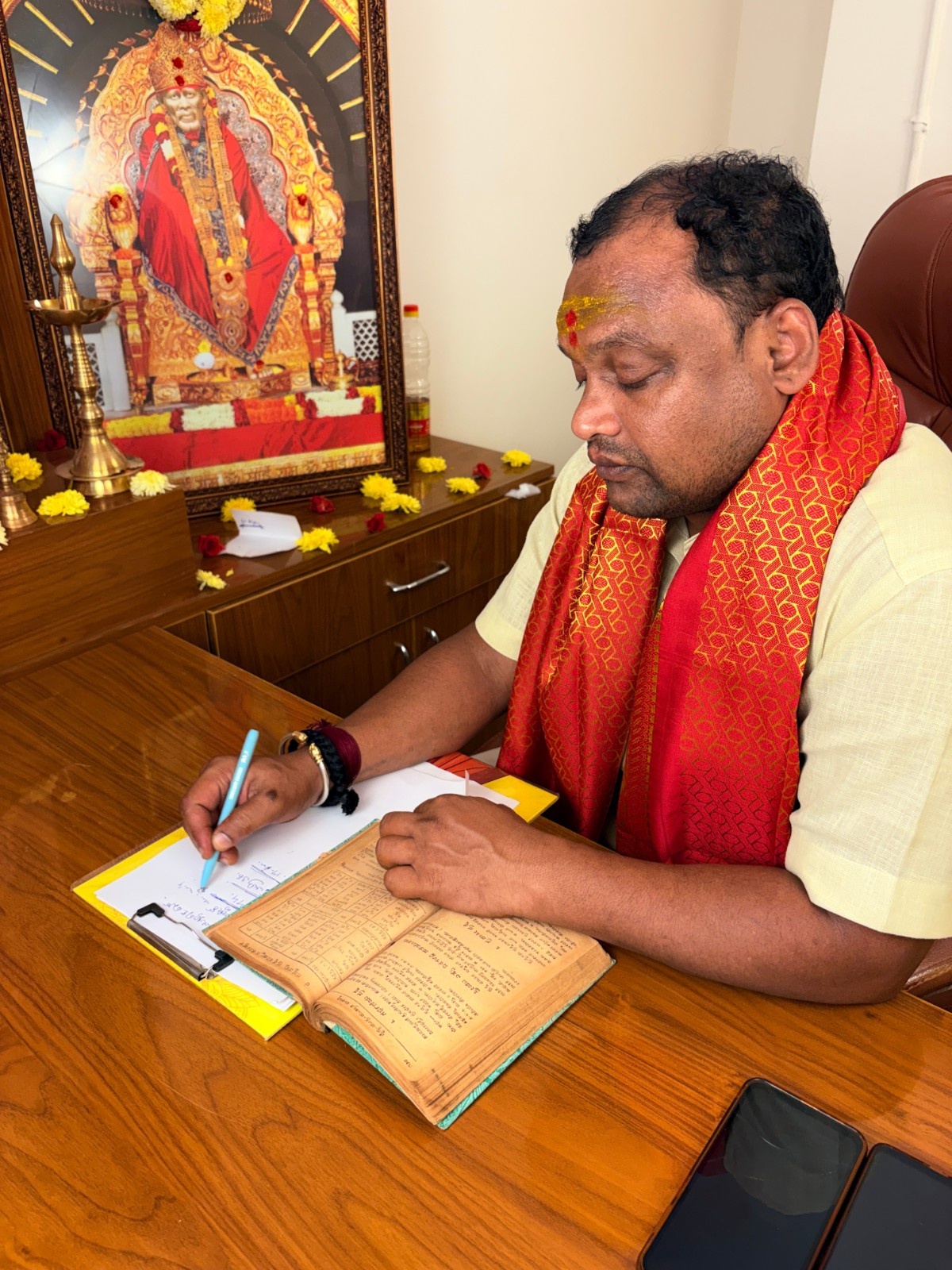 Astrologer writing notes beside devotional images